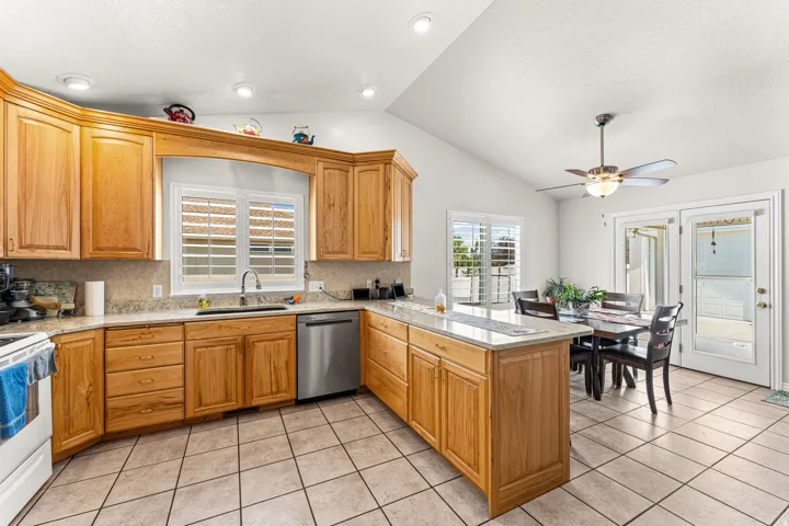 Well-appointed kitchen featuring wood cabinetry, granite-finish countertops, and a tiled backsplash