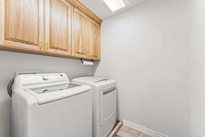 Laundry area featuring overhead wood cabinetry and tile flooring
