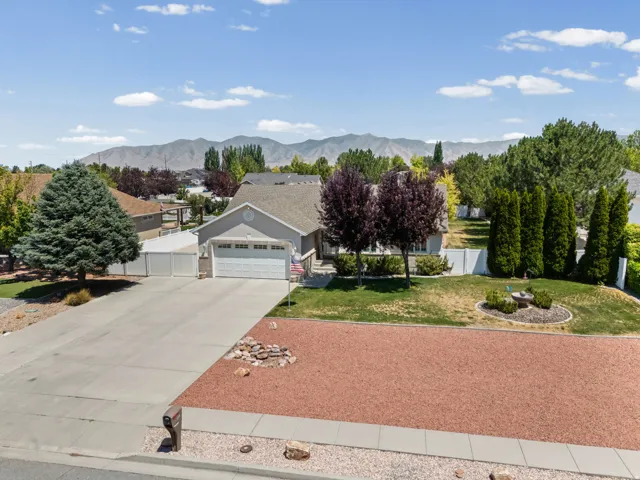 Single-story residence featuring a two-car garage, mature landscaping, and a substantial paved driveway