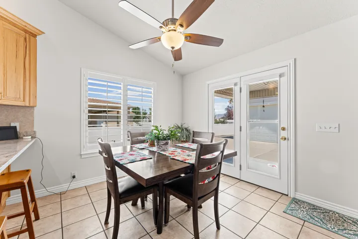 Dining area featuring vaulted ceilings, a ceiling fan with integrated lighting, and tile flooring
