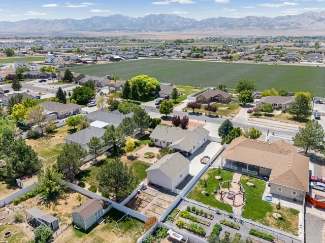 Expansive property featuring a cultivated garden, mature trees, a detached shed, paved driveway, and mountain backdrop