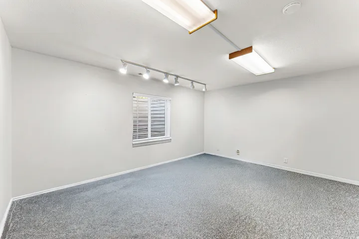 Spacious room with light gray carpeting and white walls