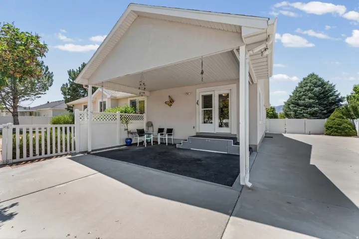 Covered patio with an aggregate surface, featuring white French doors and a low-rise step entry