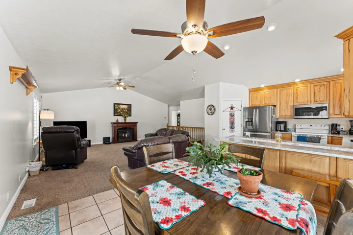 Open-concept living area with vaulted ceilings, a fireplace, and ceiling fans