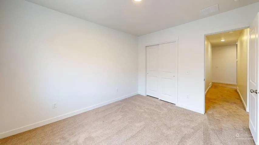 Carpeted room featuring a white bi-fold closet and a light-colored wall
