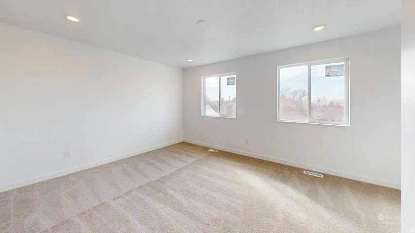 Expansive room featuring two large windows, recessed ceiling lighting, and neutral carpeting
