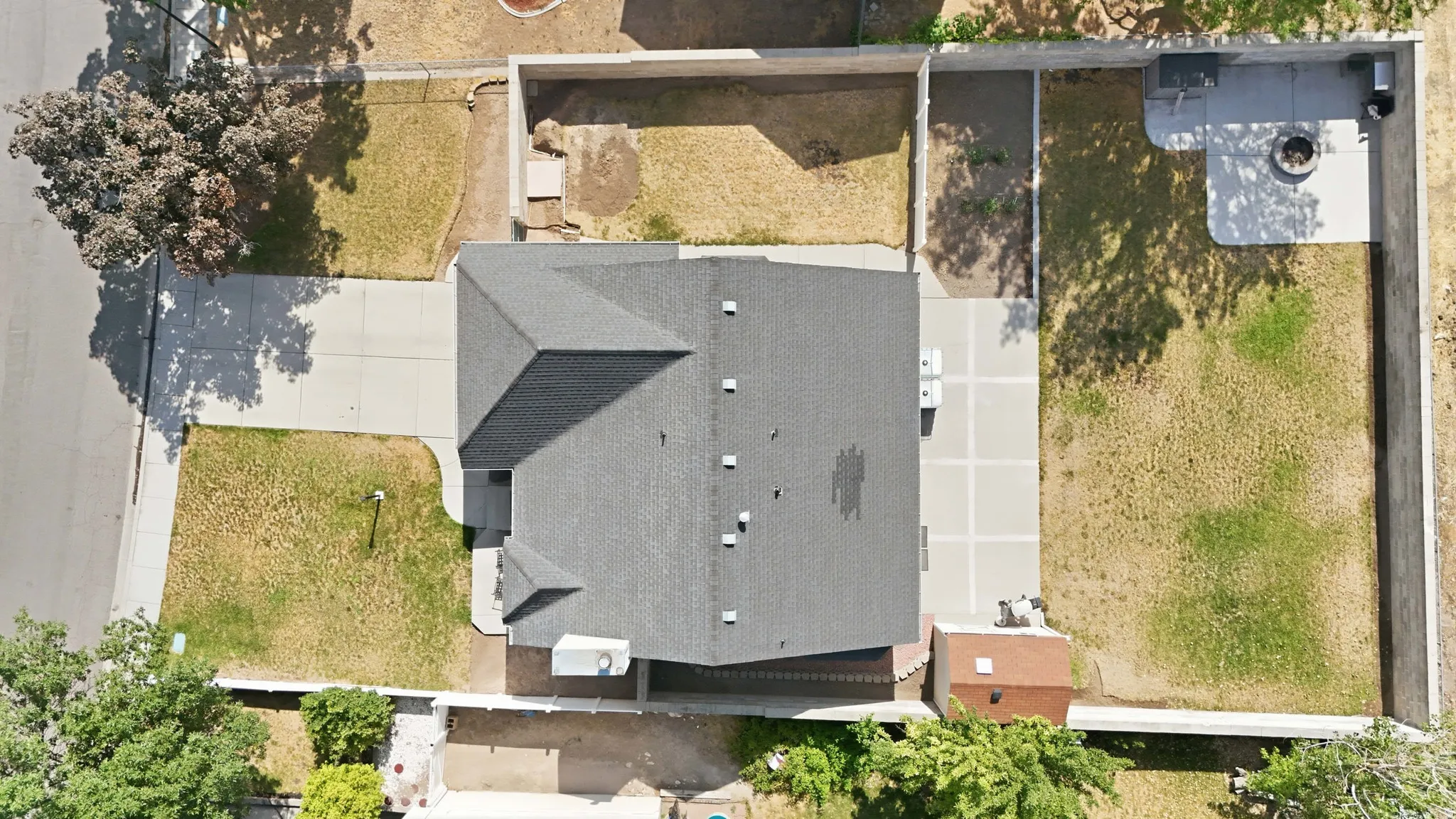 Gable roofline house with an attached two-car driveway, a concrete patio with a fire pit, and a grass lawn