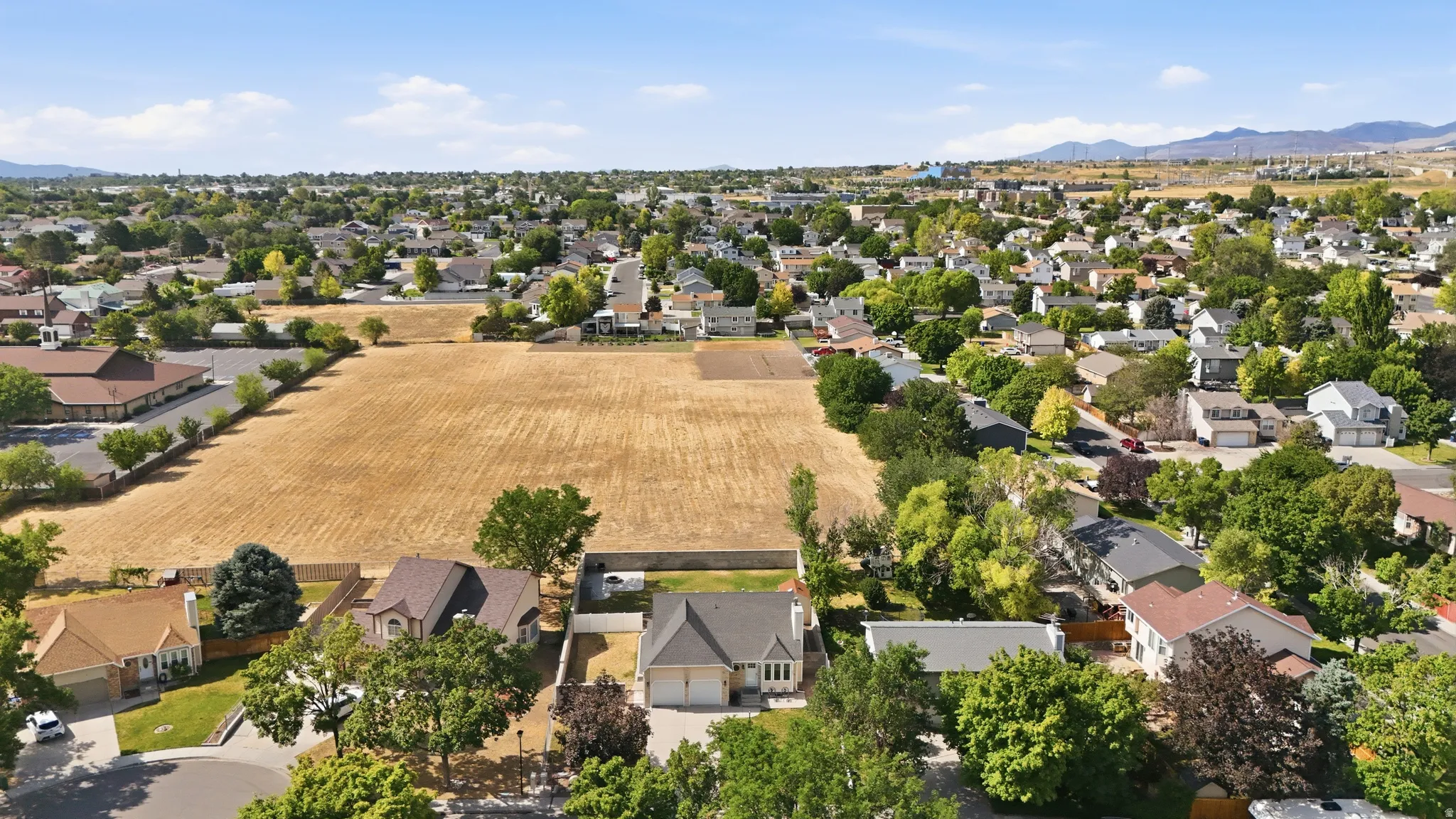 Residential neighborhood featuring a variety of single-family homes, mature trees, and a large open field