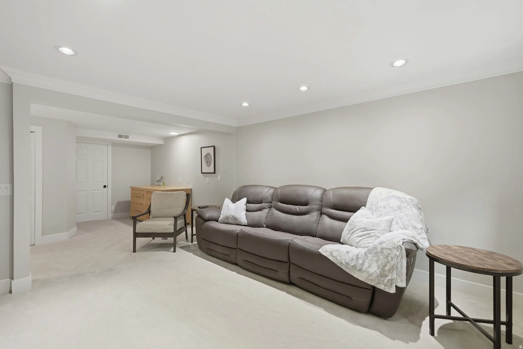 Recessed lighting illuminates a spacious room featuring light-toned carpeting and neutral wall colors