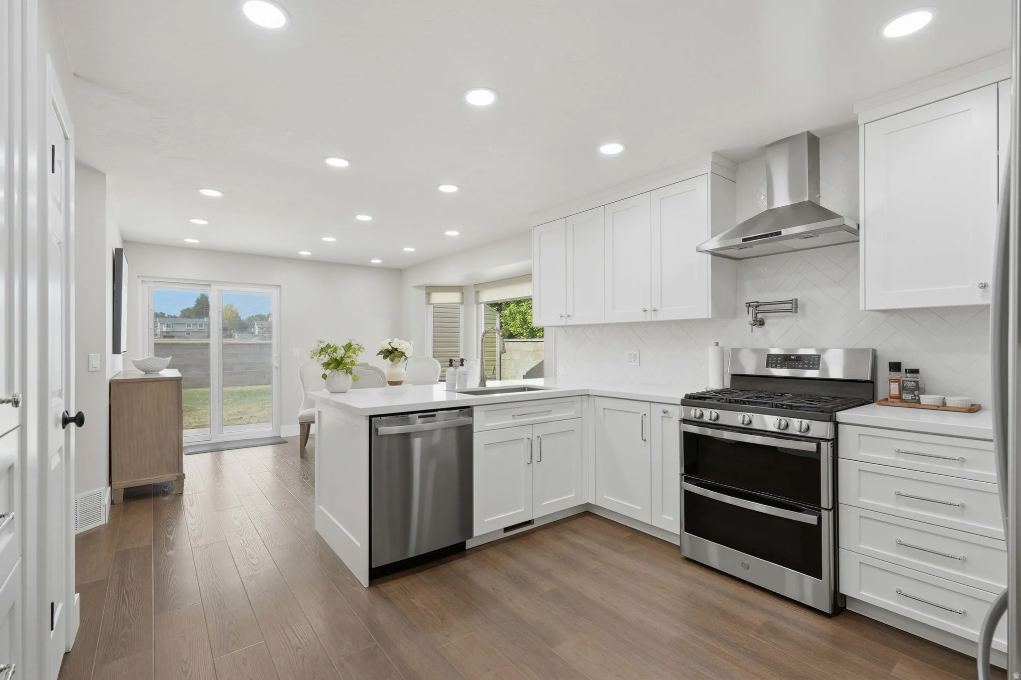 Modern kitchen featuring white shaker cabinetry, stainless steel appliances, a center island, recessed lighting, and wood-finish flooring