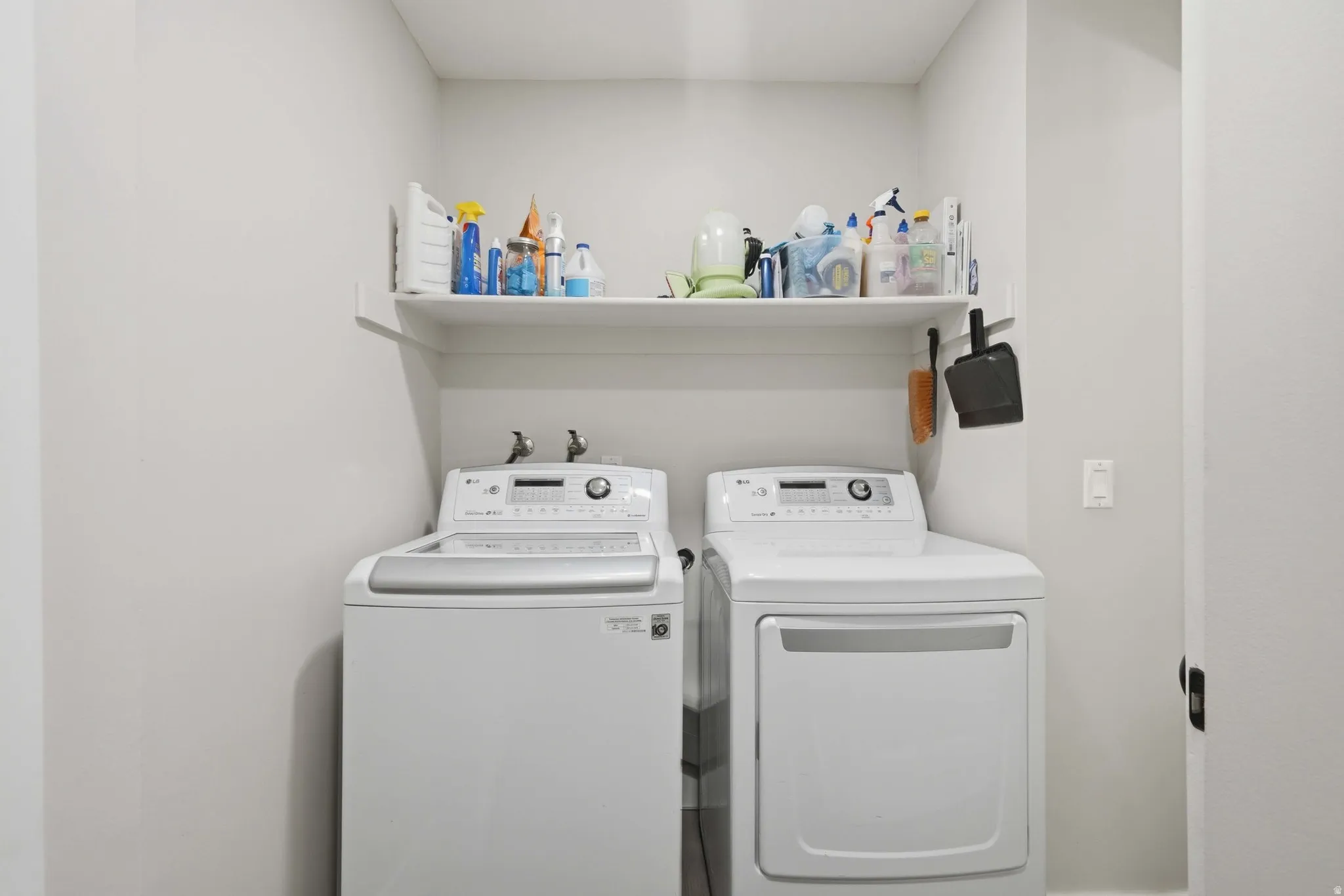 Dedicated laundry area featuring a white floating shelf, neutral wall tones, and utility hookups