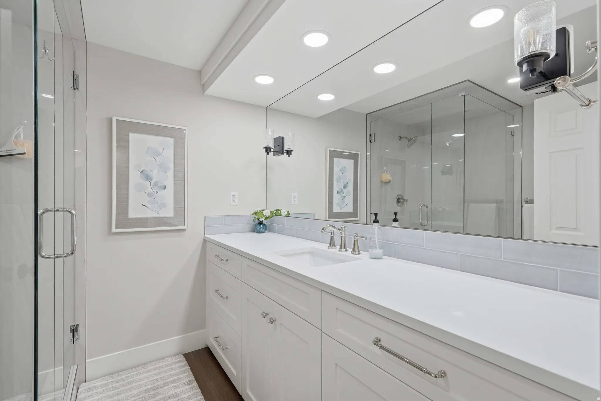 Spacious bathroom featuring an extended vanity with dual sinks, white cabinetry, and polished chrome hardware