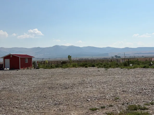 Expansive gravel lot with a red utility shed featuring a single window and white door