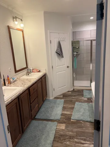 Bathroom featuring a dual vanity with rectangular sinks and wood-finish cabinetry, a framed mirror, and overhead lighting