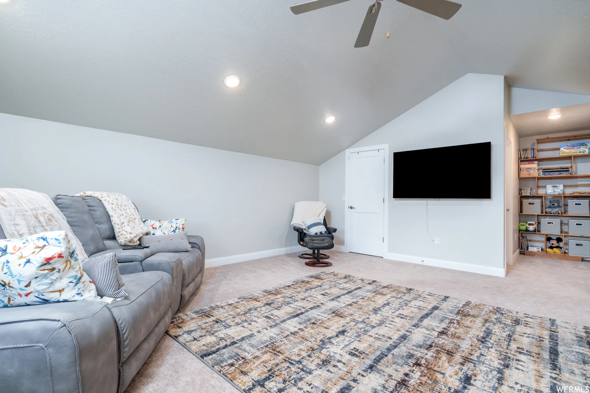 Carpeted room featuring a ceiling fan, recessed lighting, and a mounted television
