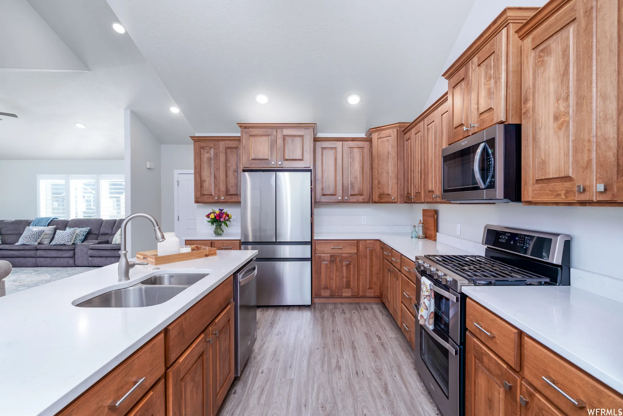 Kitchen featuring wood cabinetry, stainless steel appliances, white countertops, and wood-finish flooring