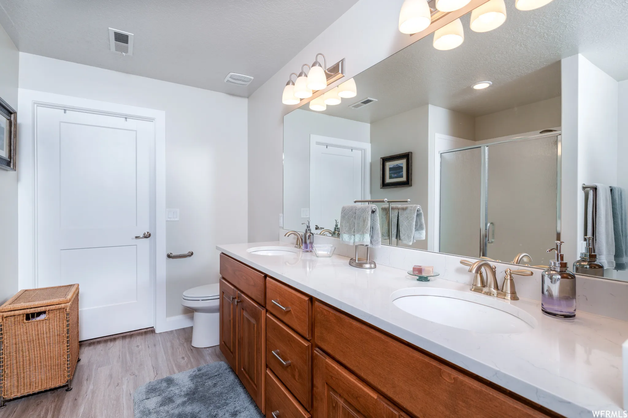 Dual vanity with white undermount sinks, bronze finish faucets, and a large mirror