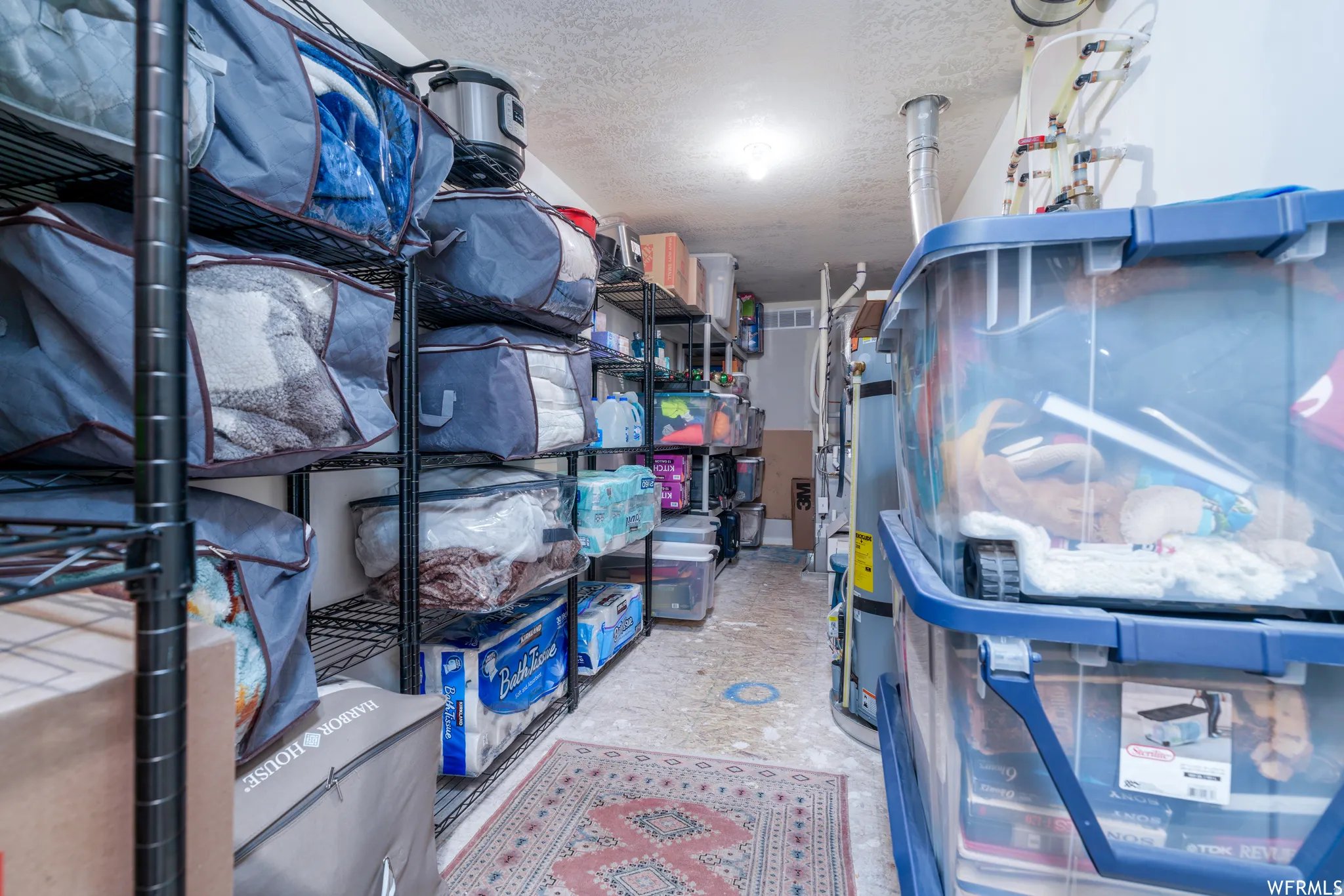 Utility room featuring wire shelving, water heater, and overhead lighting