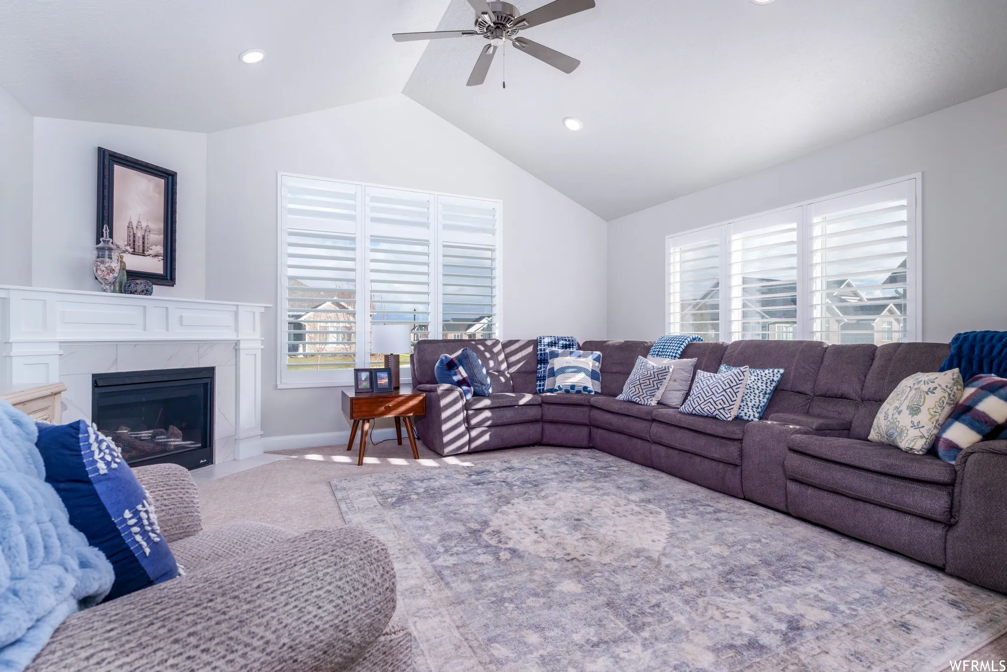 Living area featuring a vaulted ceiling with a ceiling fan, recessed lighting, and a white fireplace with a mantel