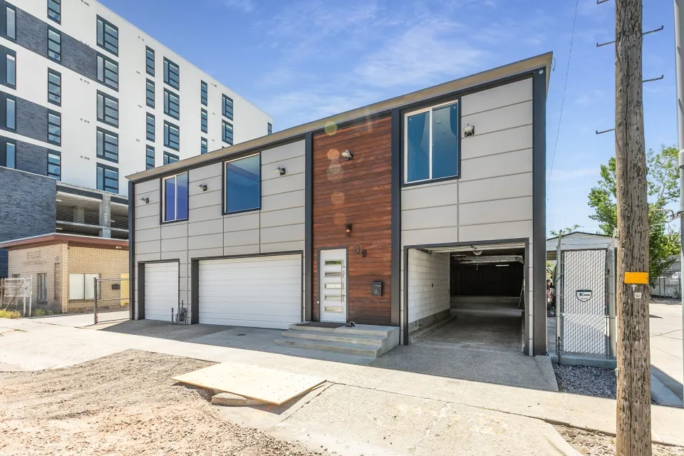 Contemporary two-story structure featuring a wood-panel accent wall and light-toned siding
