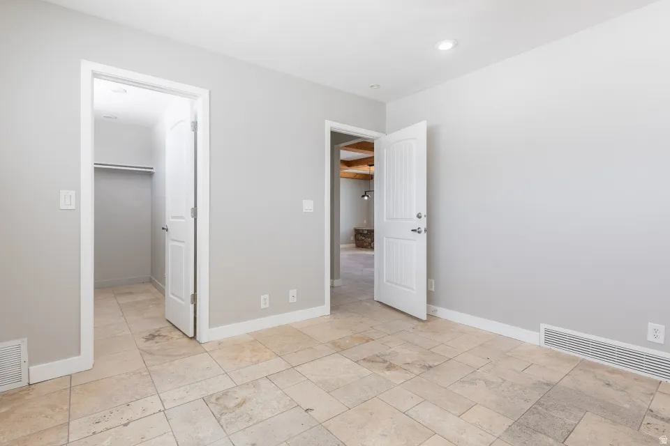 Stone tile flooring throughout, featuring a recessed ceiling light, white baseboards, and neutral wall tones