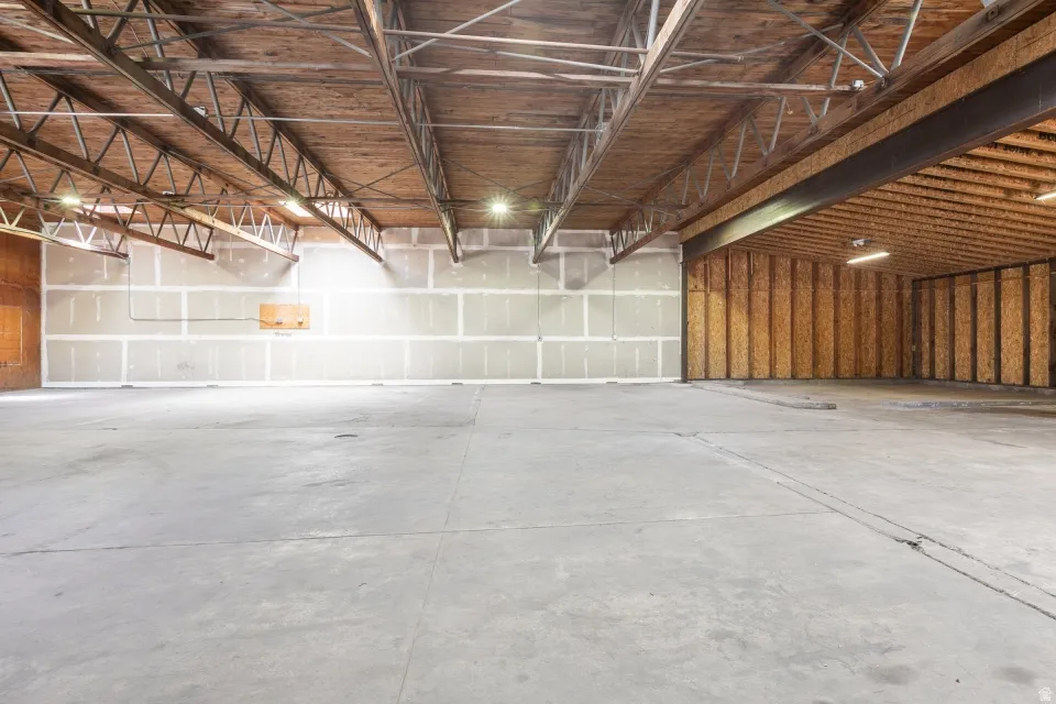 Spacious interior featuring a concrete floor, exposed wood ceiling beams, and metal truss supports