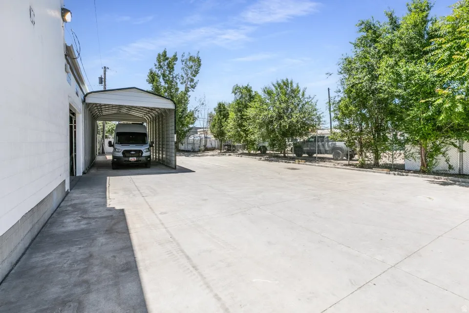 Expansive concrete lot featuring a covered carport structure