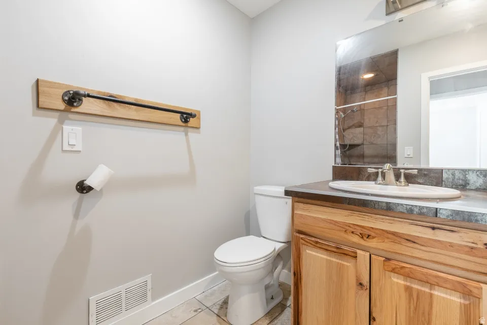Bathroom featuring a wood-finish vanity with an undermount sink, a large mirror, and industrial-style hardware