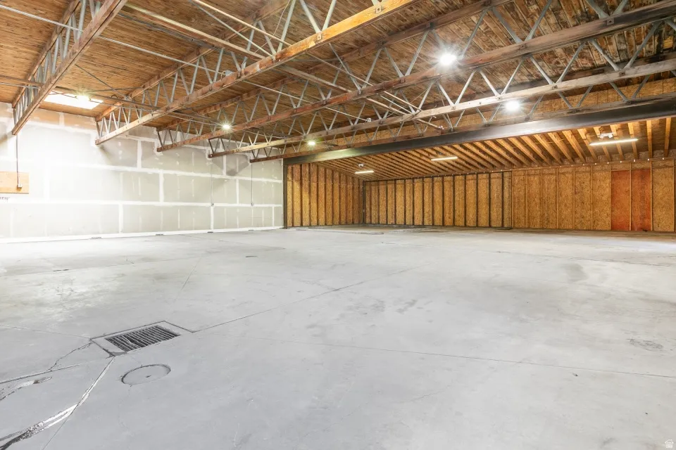 Spacious open warehouse area featuring high ceilings with exposed wood beams and metal trusses