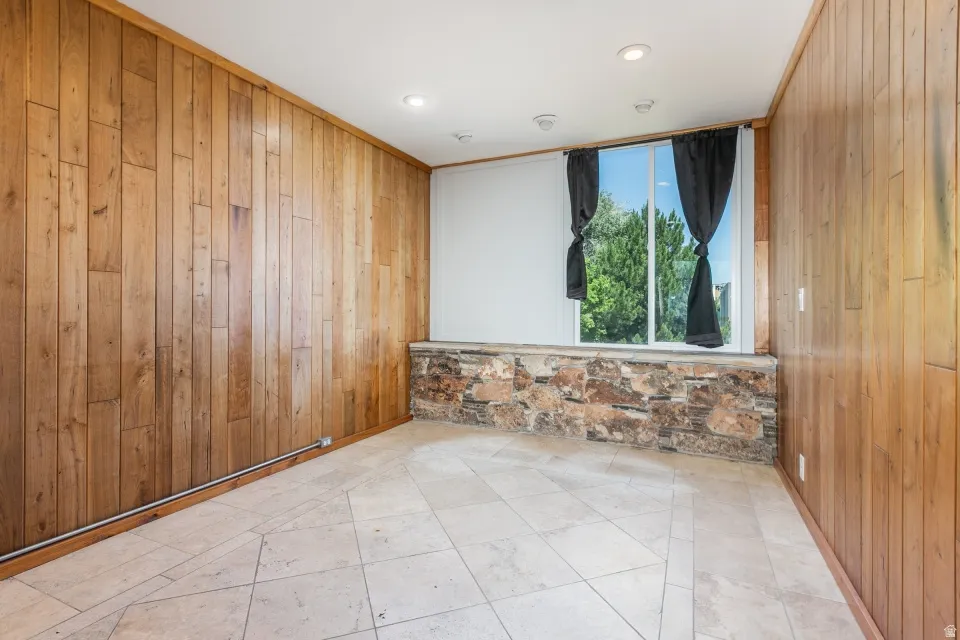 Wood paneling adorns the walls in this room, complemented by a stone accent wall below the window