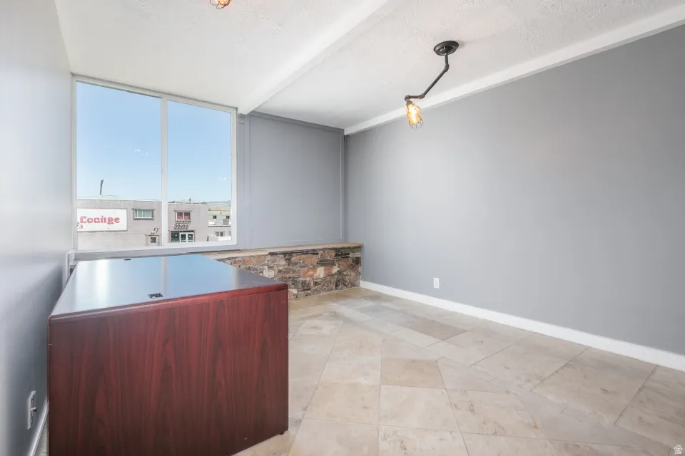 Large window providing abundant natural light, stone-clad half-wall, neutral wall paint, tile flooring, and a ceiling-mounted light fixture