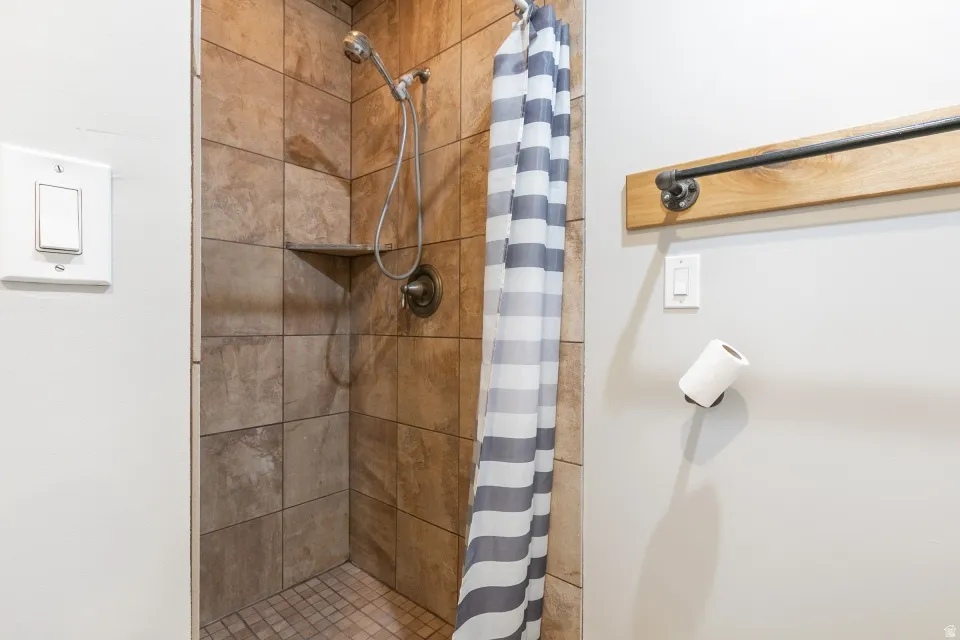 Tiled shower with handheld showerhead, built-in shelf, and contrasting floor tiling
