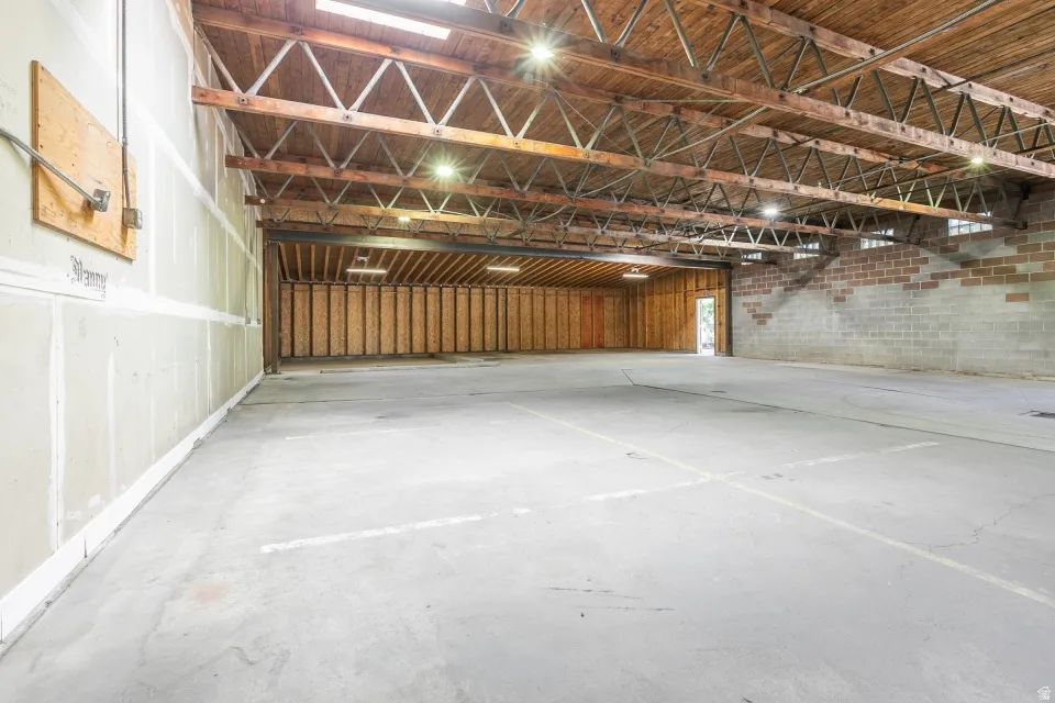Expansive open interior space featuring a concrete floor, exposed wood beam ceiling, and skylights