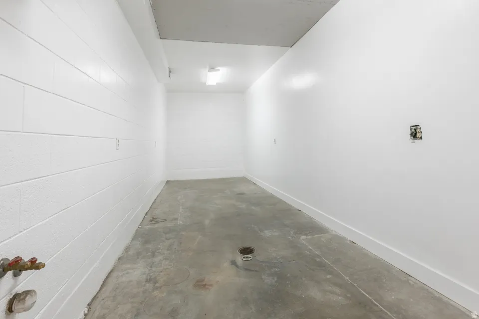 Utility space featuring concrete flooring, white painted block walls, and white painted drywall