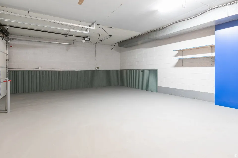 Spacious garage with concrete flooring, painted cinder block walls, and corrugated wainscoting