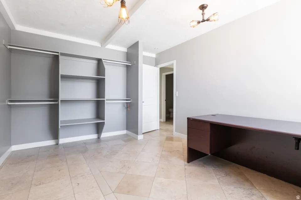 Room featuring built-in shelving, two hanging rods, and tile flooring