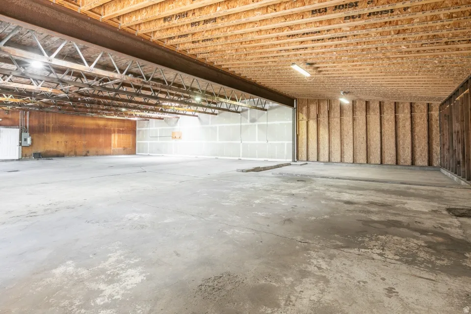Spacious commercial interior featuring a concrete floor, exposed wood ceiling joists, overhead lighting, and an expansive open layout
