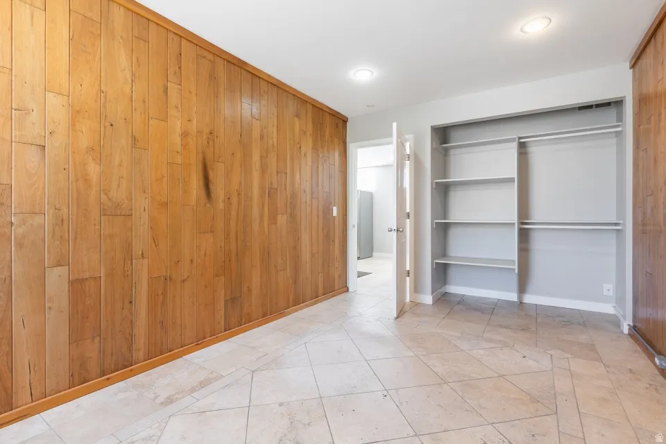 Stone-look tile flooring throughout a room featuring a full wall of wood paneling