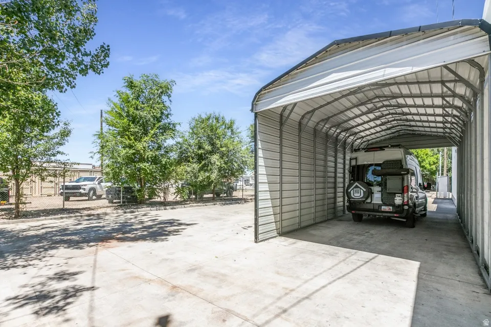 Expansive concrete parking pad featuring a large, covered metal carport
