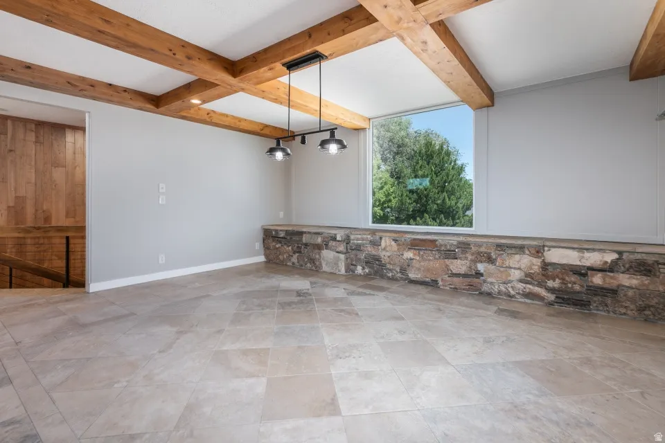 Exposed wood ceiling beams, a broad picture window, and a stone-faced partial wall with a stone cap