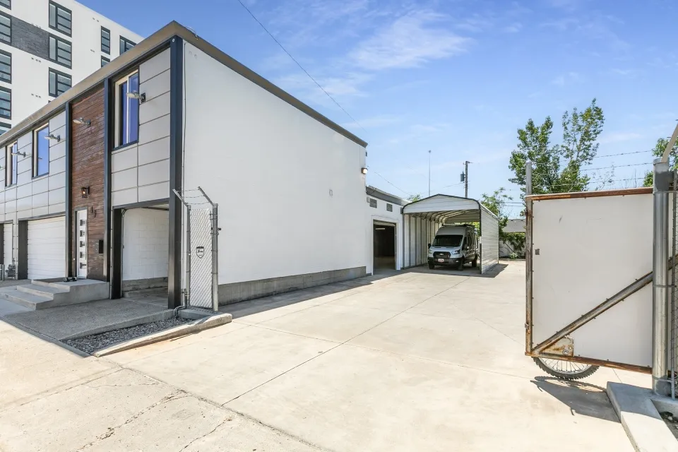 Modern exterior with integrated garage, concrete driveway, and an additional metal carport structure