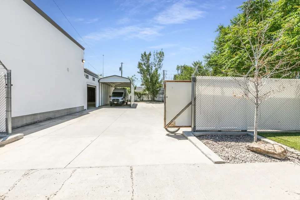 Expansive concrete driveway leading to a covered carport and building entrance