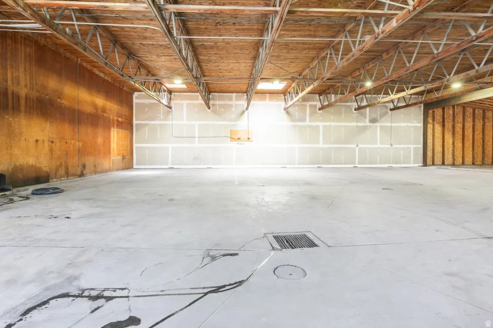 Expansive open-concept interior featuring a concrete floor, exposed wood ceiling trusses, and recessed lighting