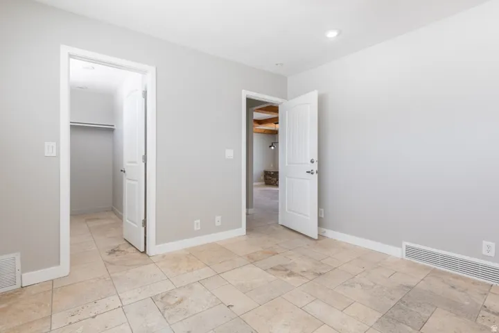 Stone tile flooring throughout, featuring a recessed ceiling light, white baseboards, and neutral wall tones