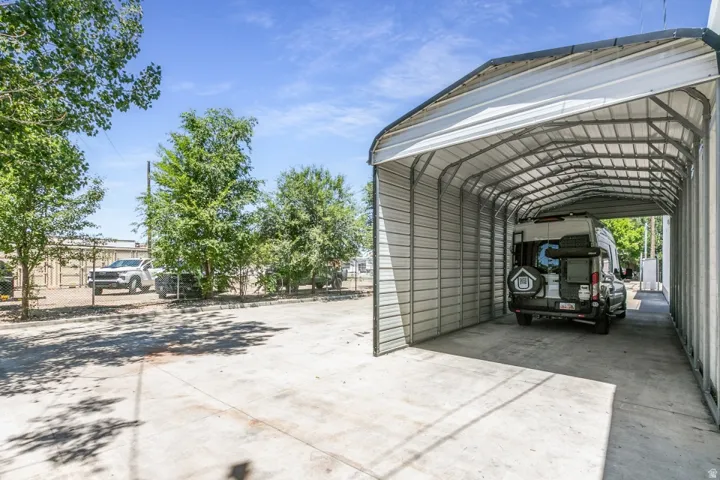 Expansive concrete parking pad featuring a large, covered metal carport