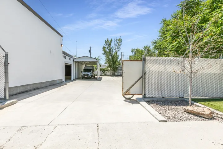 Expansive concrete driveway leading to a covered carport and building entrance