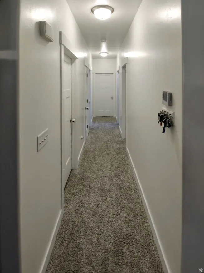 Hallway featuring light-toned plush carpet flooring