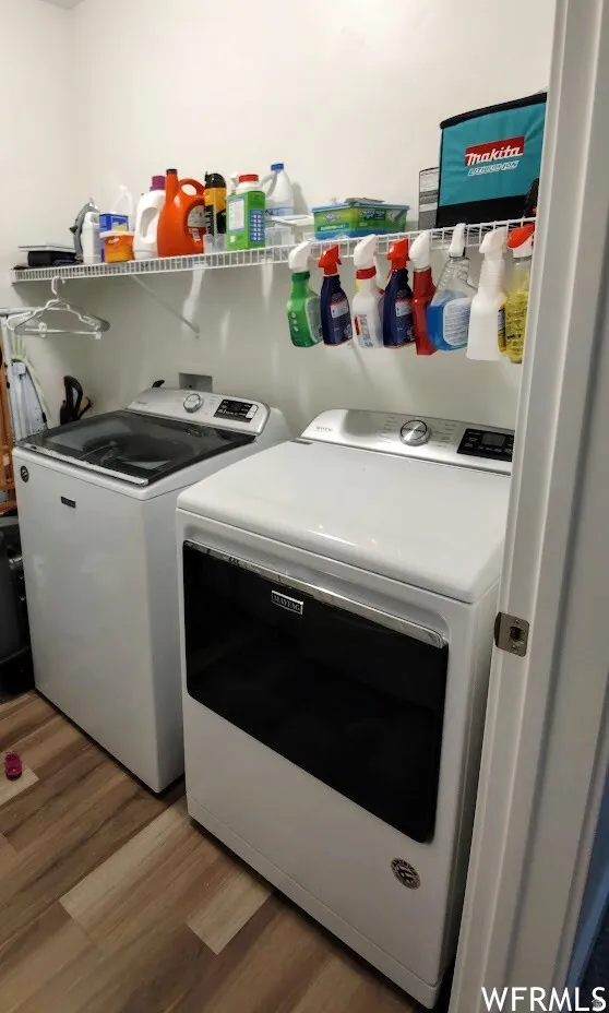 Dedicated laundry area featuring wood-finish flooring, white walls, and a convenient wire shelving system