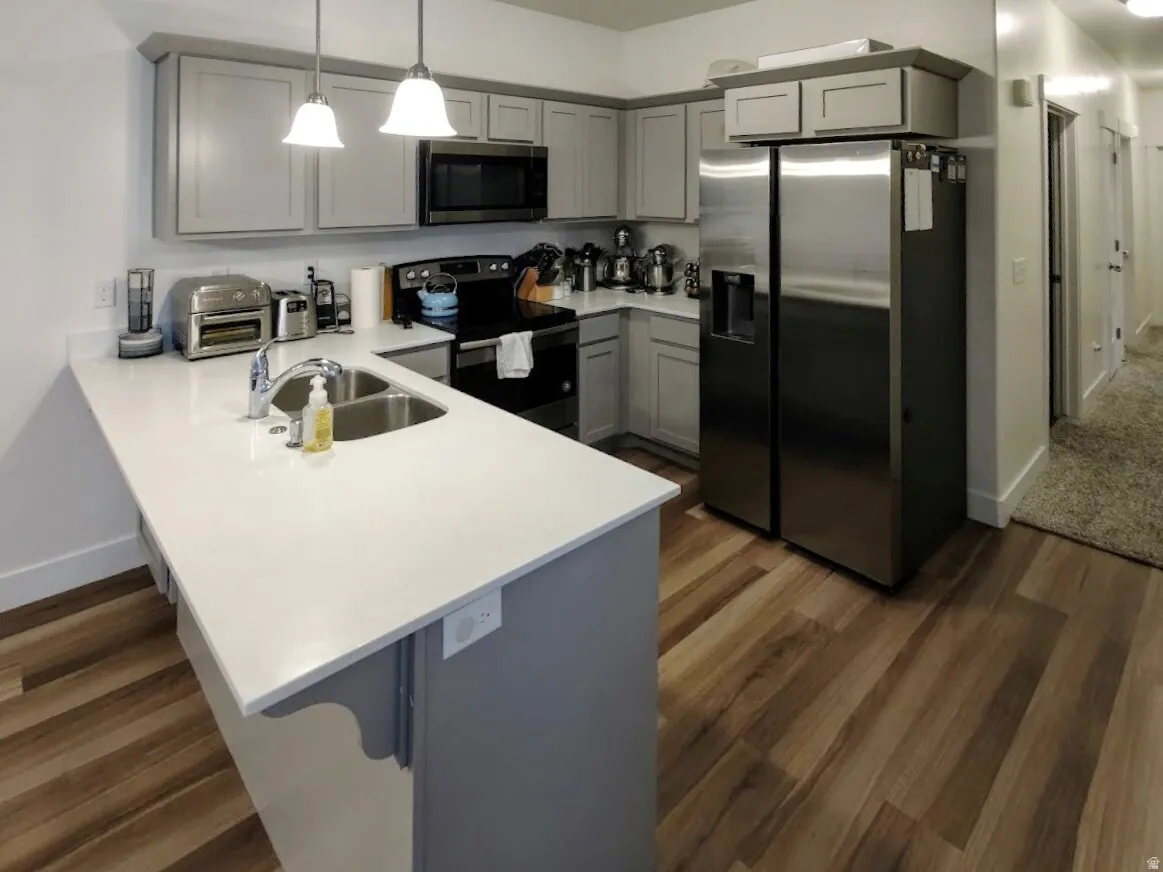 Modern kitchen featuring light gray cabinetry with dark gray trim, stainless steel appliances, and white countertops