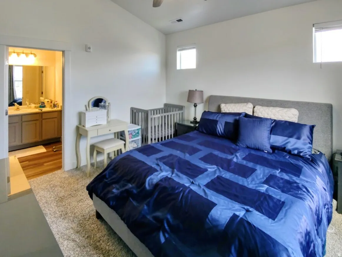 Spacious bedroom featuring light-colored walls, carpet flooring, and two high-set windows providing natural light